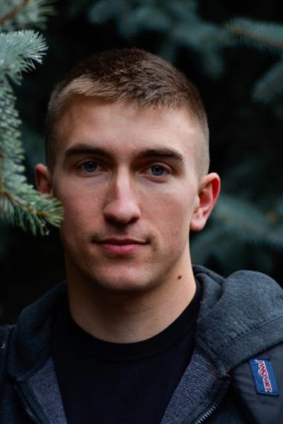 Close-up portrait of a man outdoors in an evergreen forest.